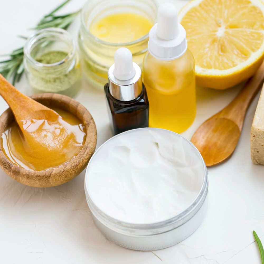 A picture of natural, organic spa ingredients, including manuka honey, soap, lotion, bath salt, rosemary branches, and lemons.