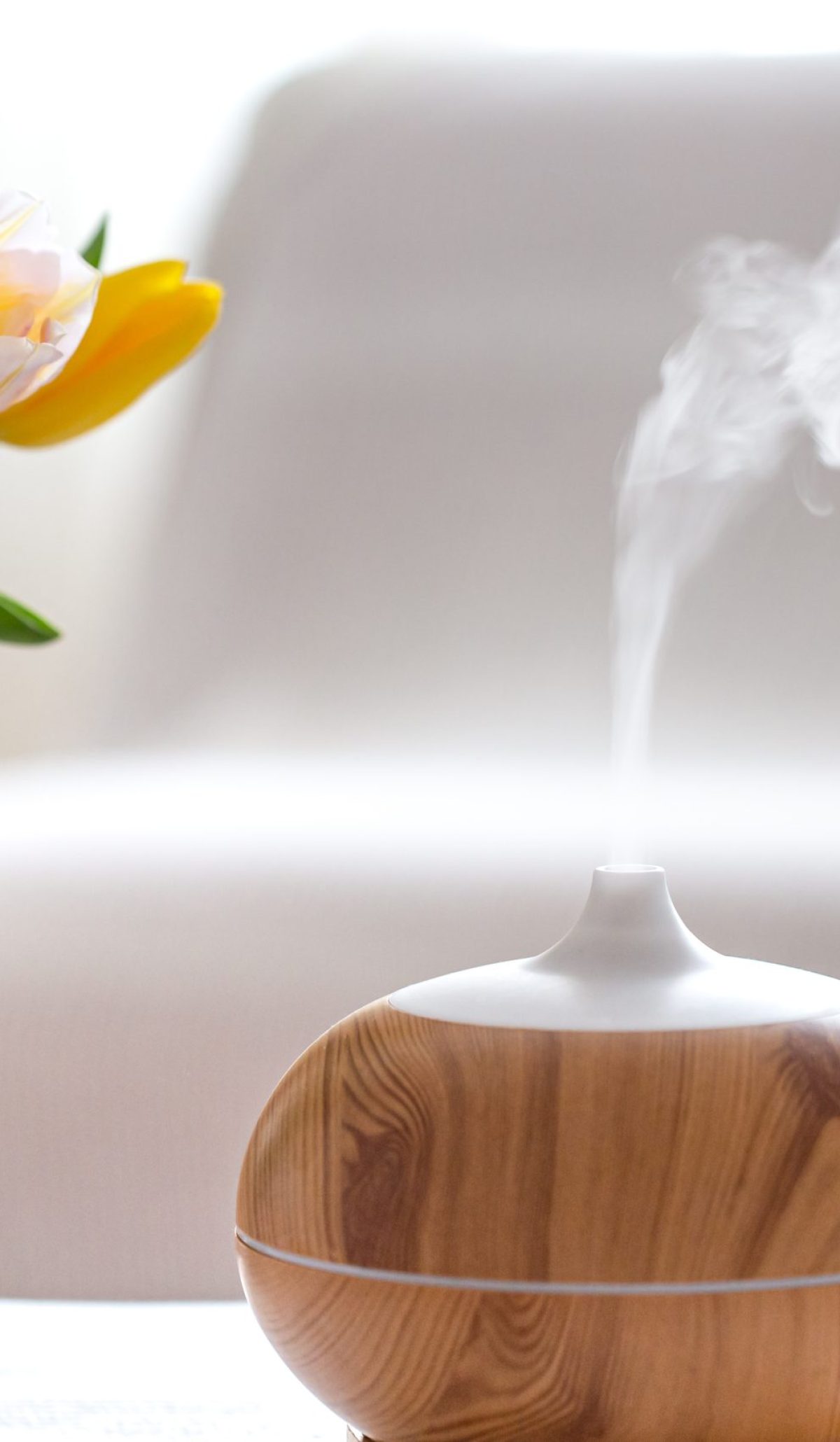 Aroma oil diffuser lamp on the table on a blurred background with a beautiful spring bouquet of tulips.