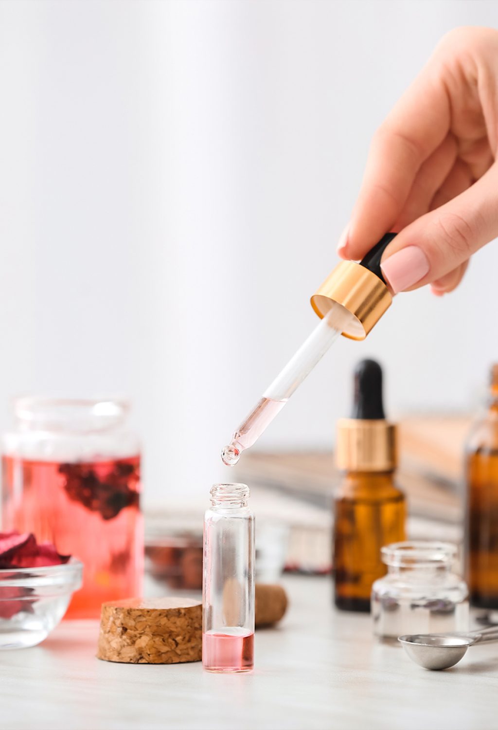 Selection of essential oils with various herbs and flowers in the background